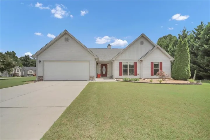 White siding exterior with a prominent front entrance, an attached two-car garage, and a concrete driveway