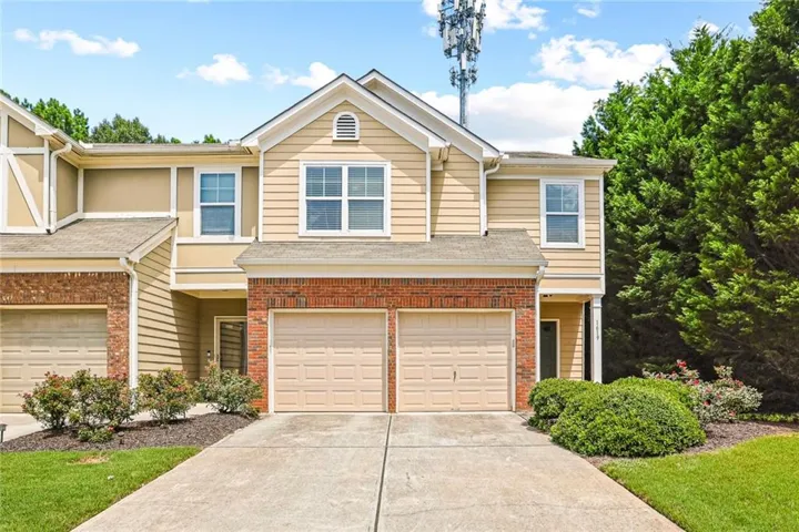 Siding exterior with brick accents, two-car garage, concrete driveway, and established landscaping