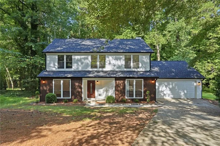 Two-story exterior with white siding, dark lower-level facade, and a dark shingle roof