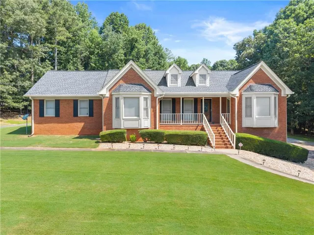 Brick exterior with bay windows, a covered front porch, and dormer windows