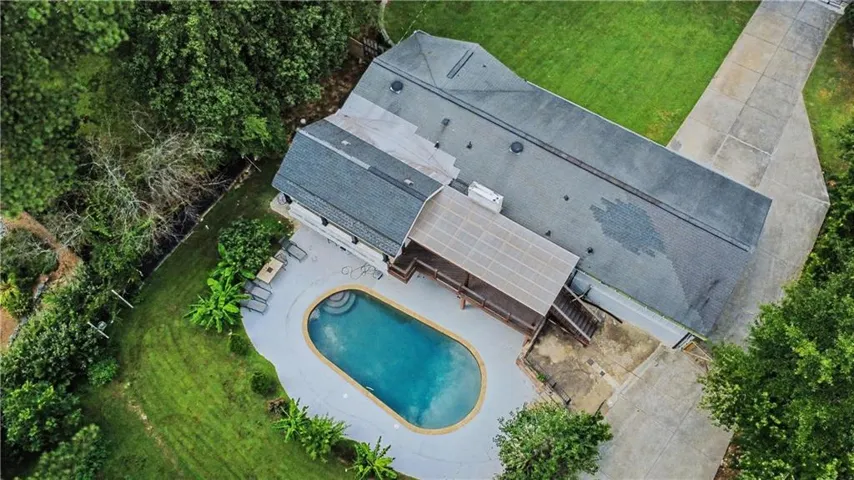 Expansive outdoor area featuring an oval-shaped swimming pool with integrated steps, surrounded by a concrete patio