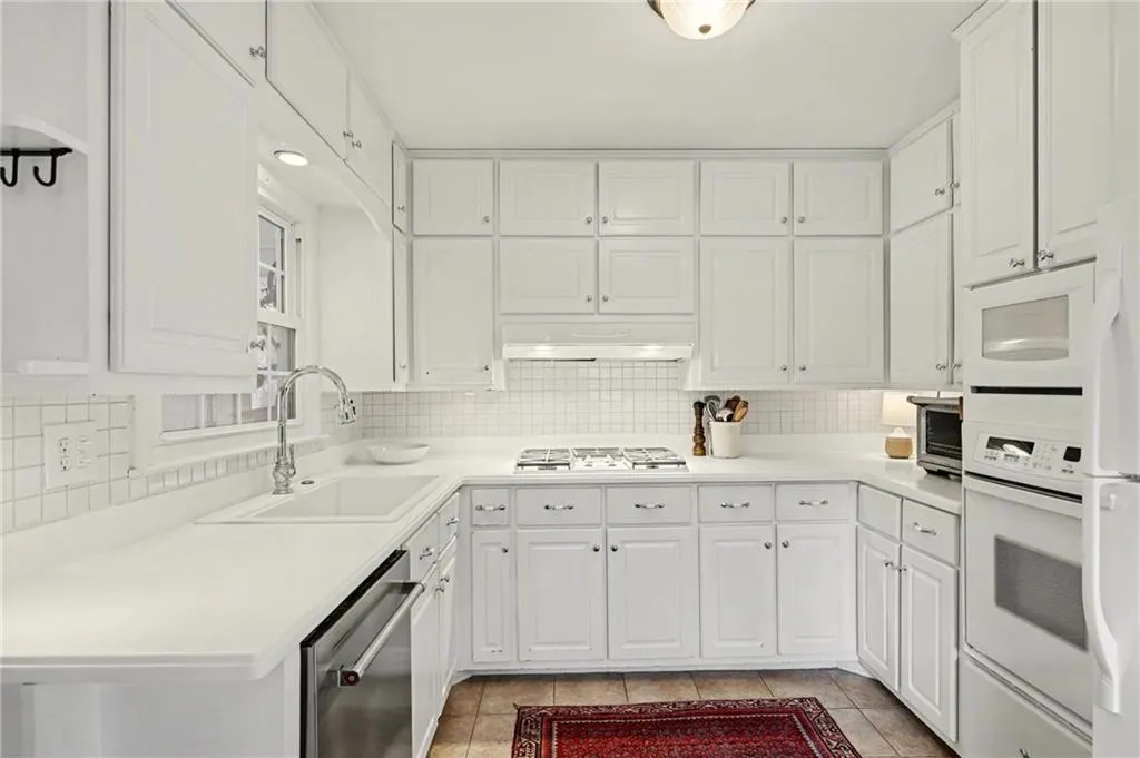 Kitchen featuring light countertops, decorative backsplash, white cabinetry, and appliances with stainless steel finishes