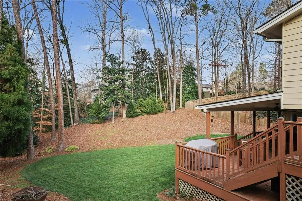 View of green lawn featuring a wooden deck
