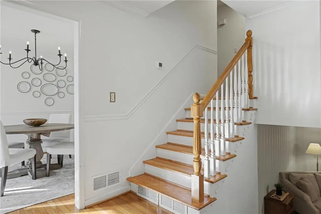Stairs featuring crown molding, wood finished floors, and a chandelier