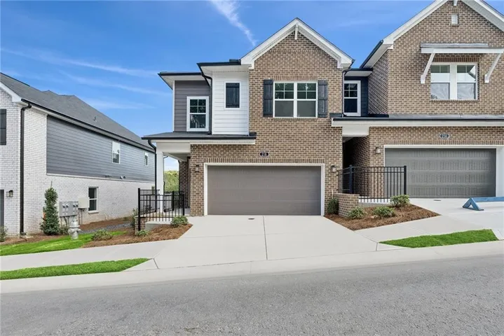 Brick and siding exterior with gabled roofline, front-facing attached garage, and paved driveway