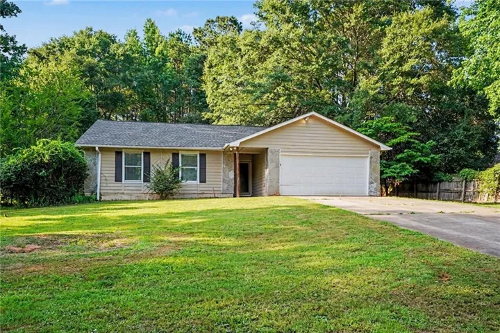 Ranch-style exterior with a gabled roof, two-car garage, stone facade accents, and a paved driveway