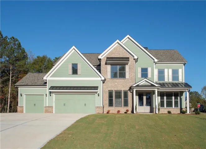 Two-story residence featuring brick and siding facade, a two-car garage, and a covered front entry