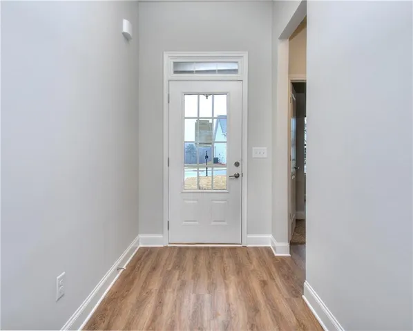 Doorway with wood finished floors and baseboards