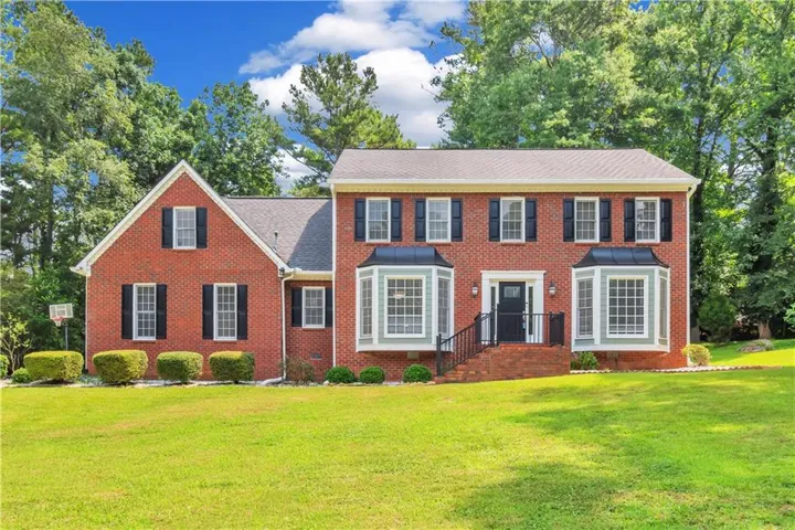 Red brick exterior with black shutters, dual bay windows, and a prominent front entrance with brick steps and black railings