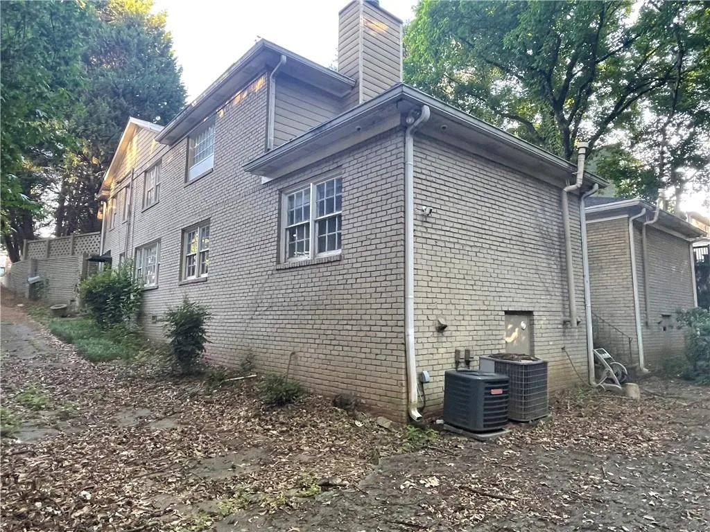 View of side of home with a chimney and brick siding