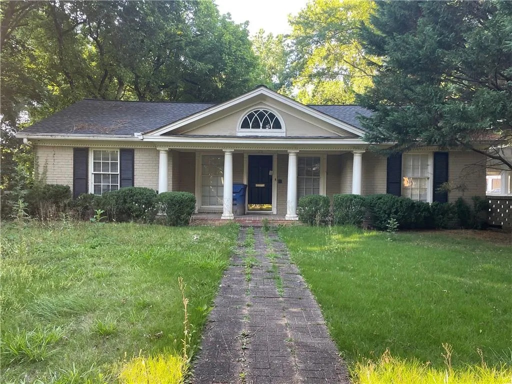 Greek revival inspired property featuring a porch, a front lawn, brick siding, and a shingled roof