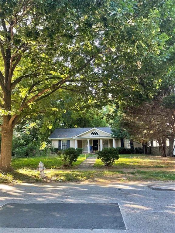 View of front of home featuring a porch and view of wooded area