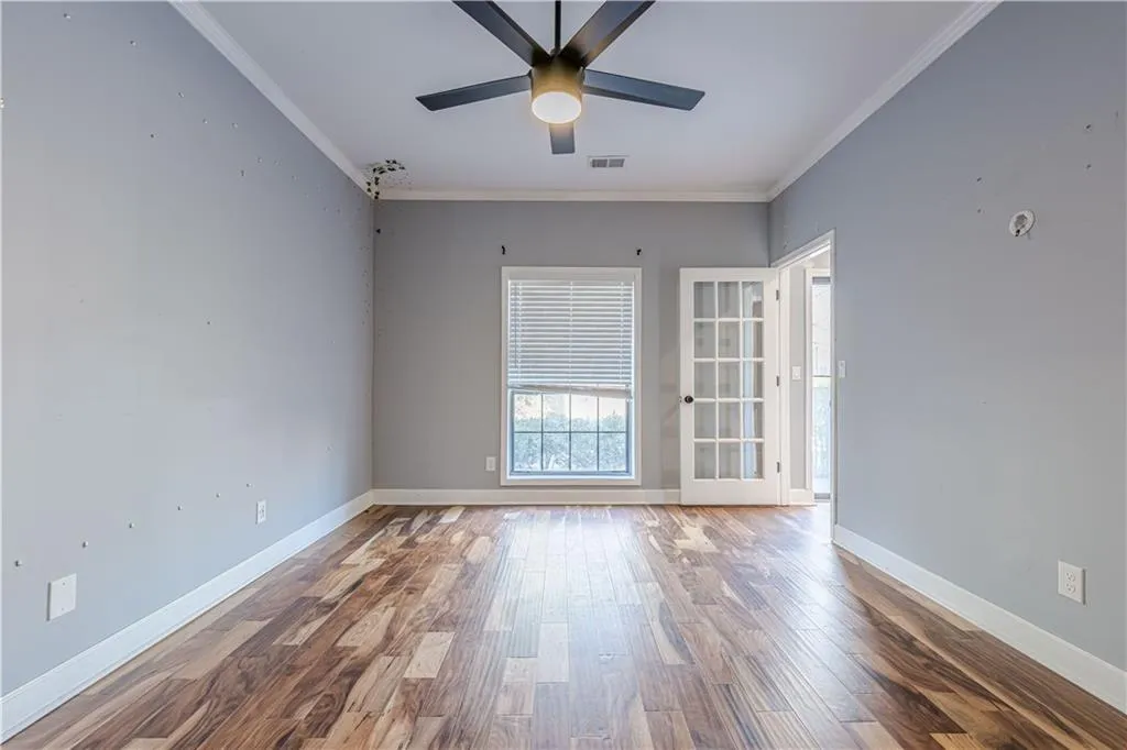 Spare room featuring visible vents, baseboards, ornamental molding, ceiling fan, and wood finished floors