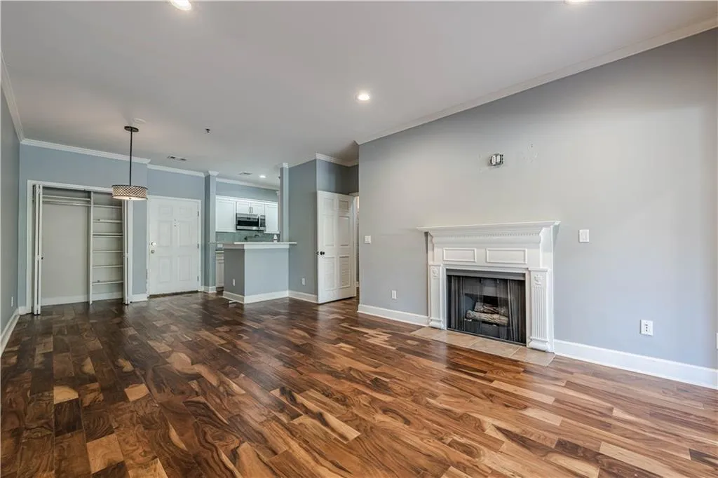 Unfurnished living room featuring a fireplace with flush hearth, dark wood-style flooring, baseboards, ornamental molding, and recessed lighting