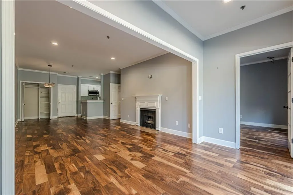 Unfurnished living room with recessed lighting, ornamental molding, a fireplace with flush hearth, dark wood-type flooring, and baseboards