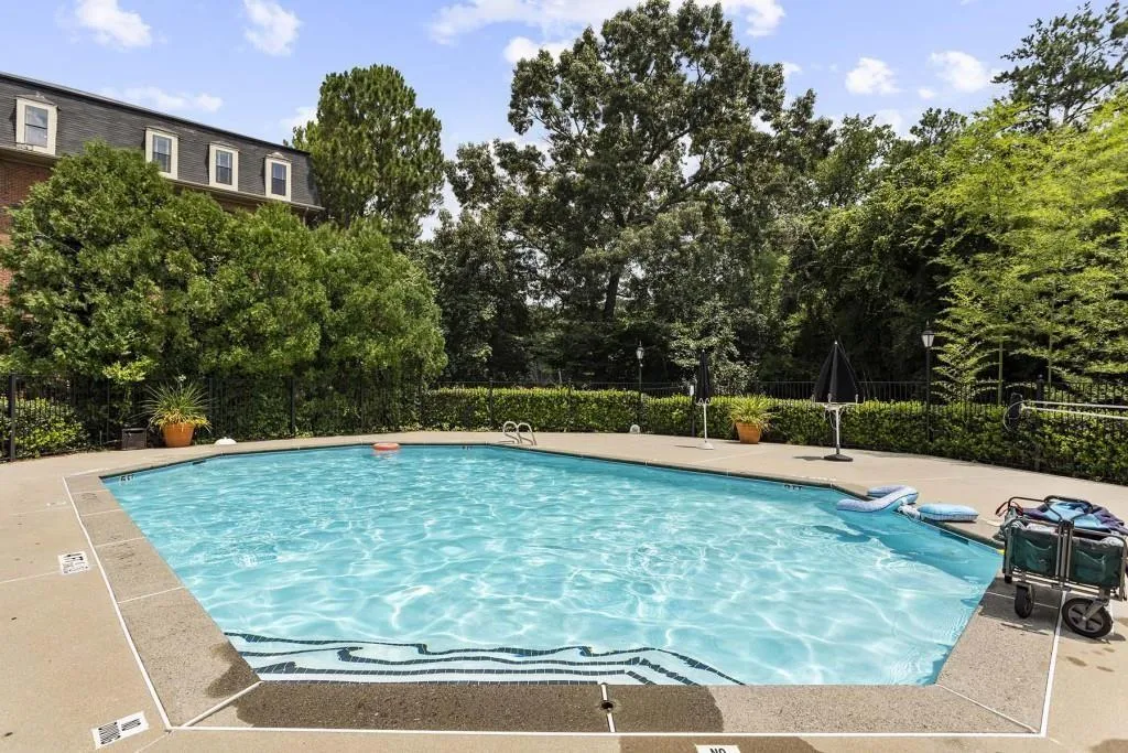 View of pool with fence and view of wooded area