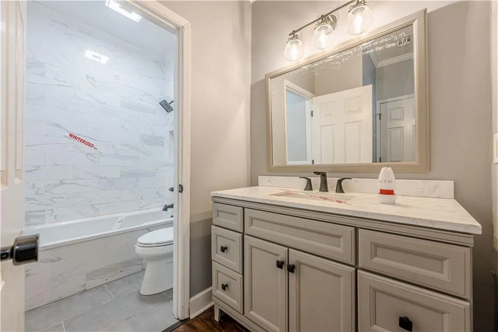 Full bath with bathing tub / shower combination, toilet, baseboards, and vanity