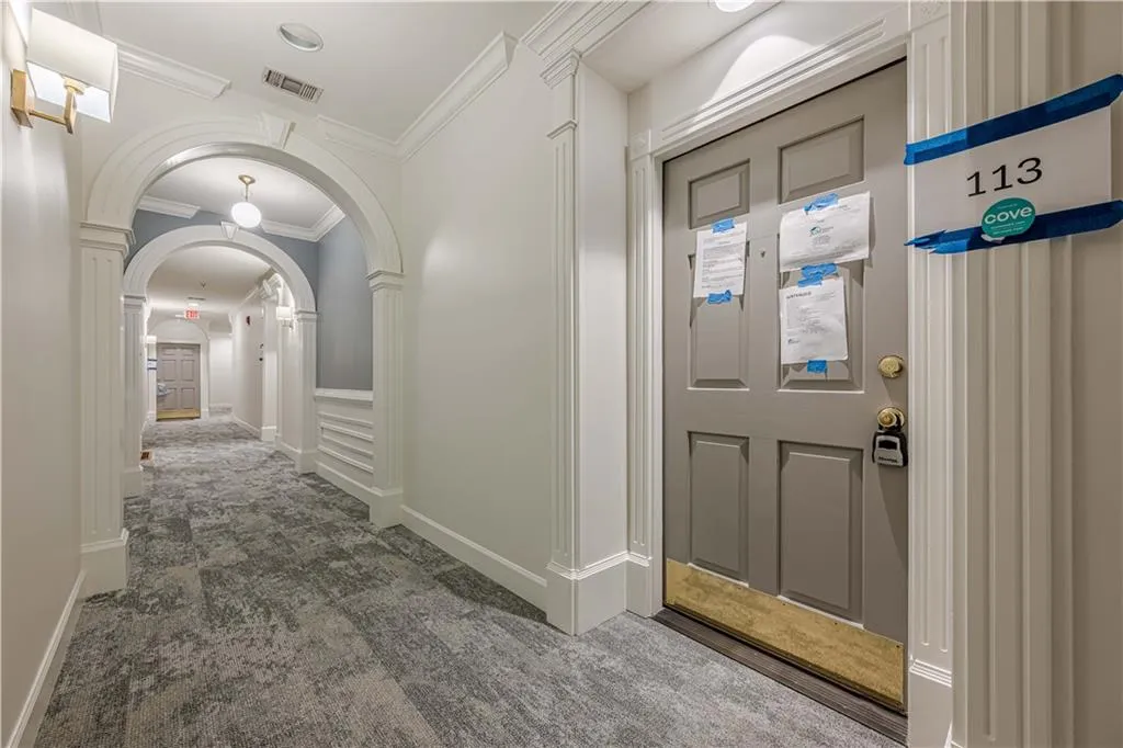 Hallway featuring visible vents, crown molding, carpet, baseboards, and arched walkways