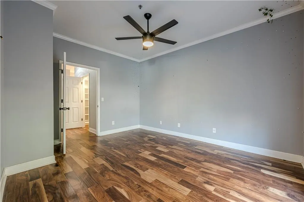 Unfurnished room with wood finished floors, ornamental molding, baseboards, and ceiling fan