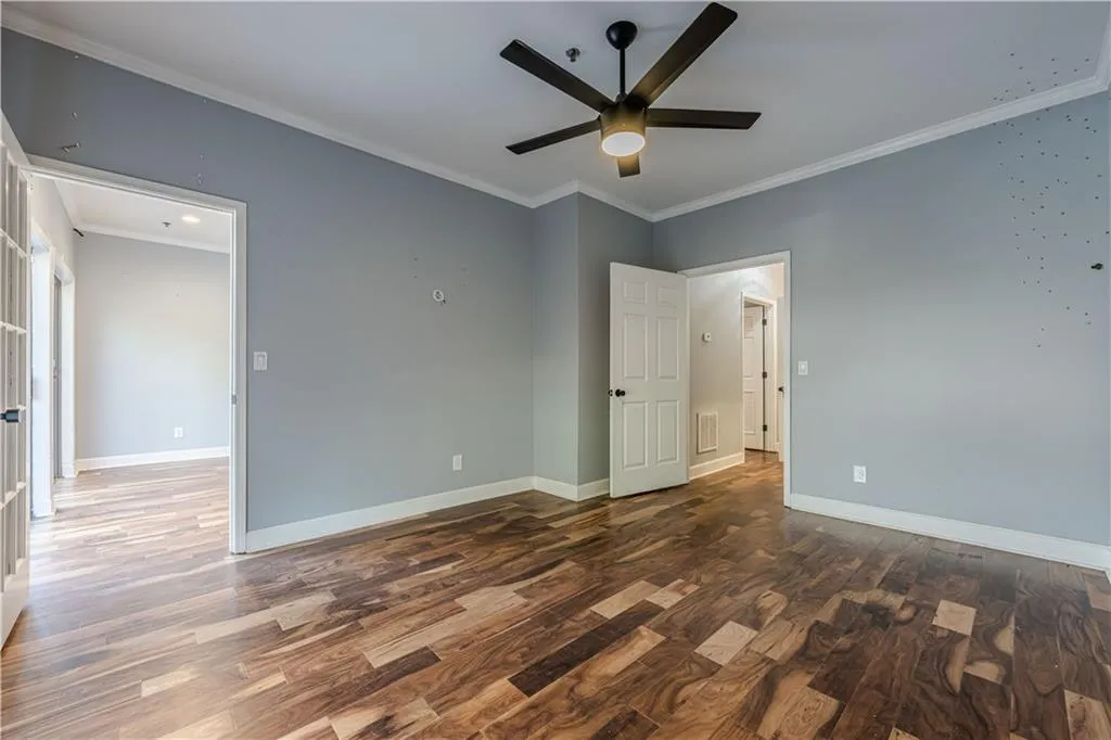 Unfurnished bedroom with baseboards, crown molding, and wood finished floors