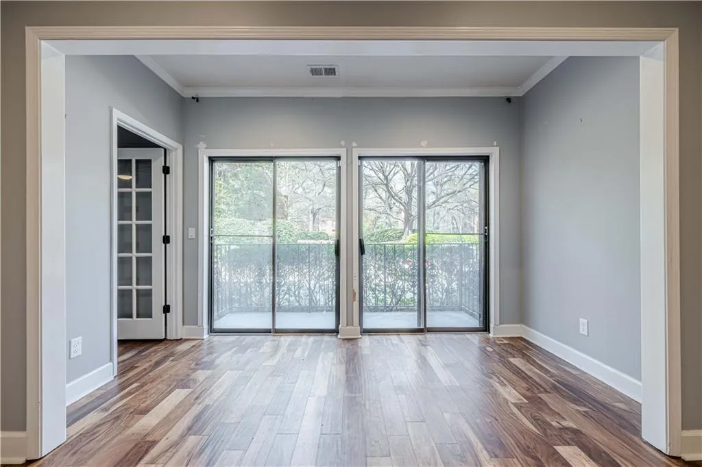 Spare room with wood finished floors, crown molding, baseboards, and visible vents