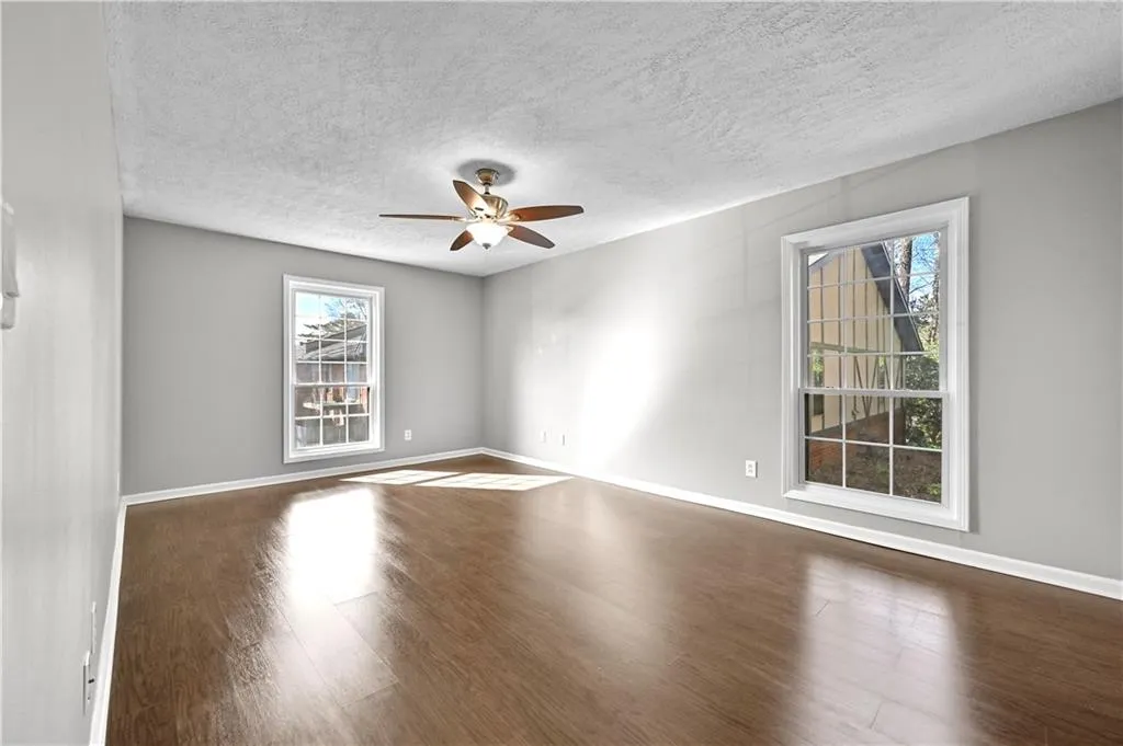 Empty room featuring a textured ceiling, dark hardwood / wood-style floors, and ceiling fan