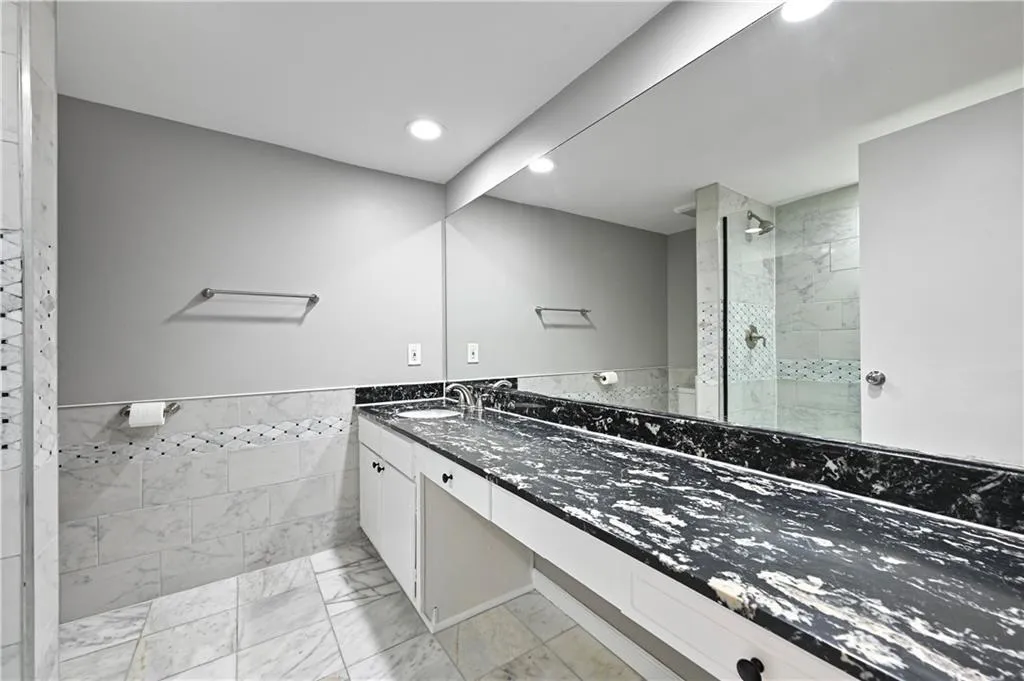 Bathroom featuring vanity, tiled shower, and tile walls