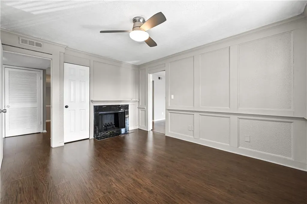 Unfurnished living room featuring dark hardwood / wood-style floors, ornamental molding, a premium fireplace, and ceiling fan