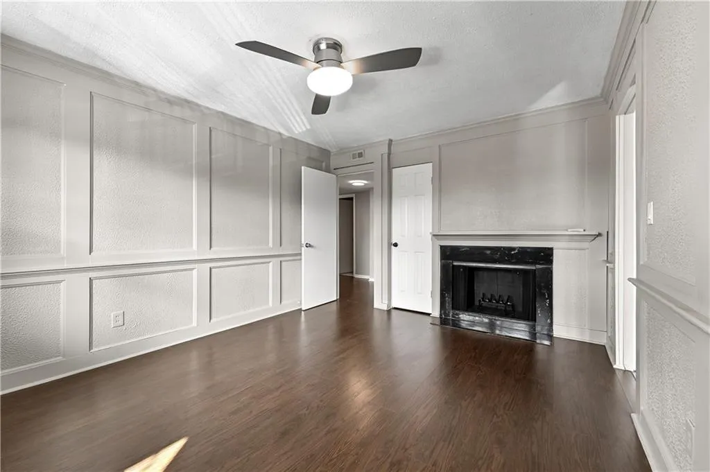 Unfurnished living room featuring ceiling fan, dark wood-type flooring, a textured ceiling, and a fireplace