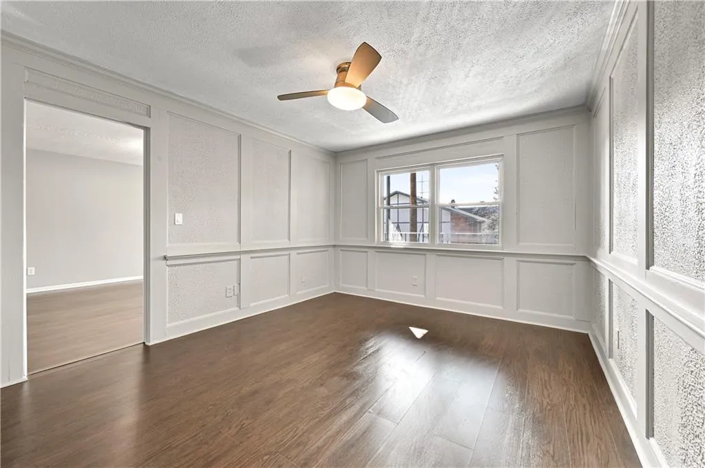 Unfurnished room with ceiling fan, dark hardwood / wood-style floors, crown molding, and a textured ceiling
