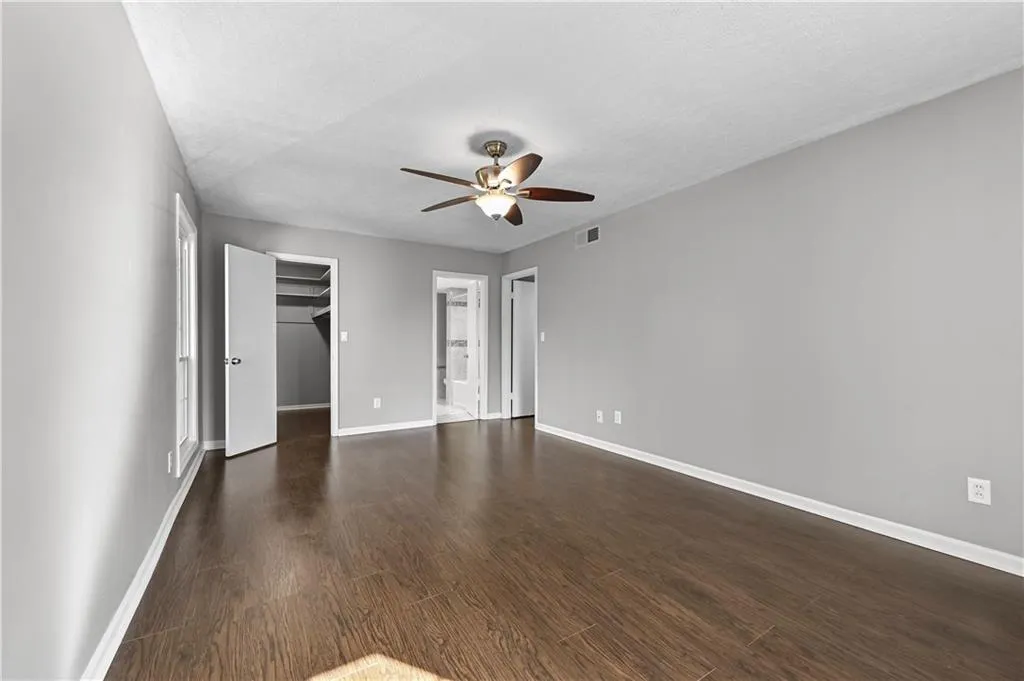 Unfurnished bedroom featuring a closet, dark hardwood / wood-style floors, a textured ceiling, and a spacious closet
