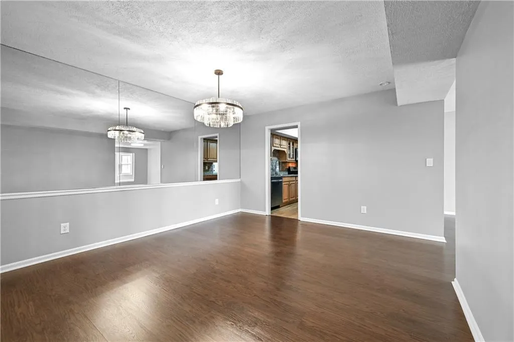 Spare room featuring dark hardwood / wood-style flooring, a notable chandelier, and a textured ceiling