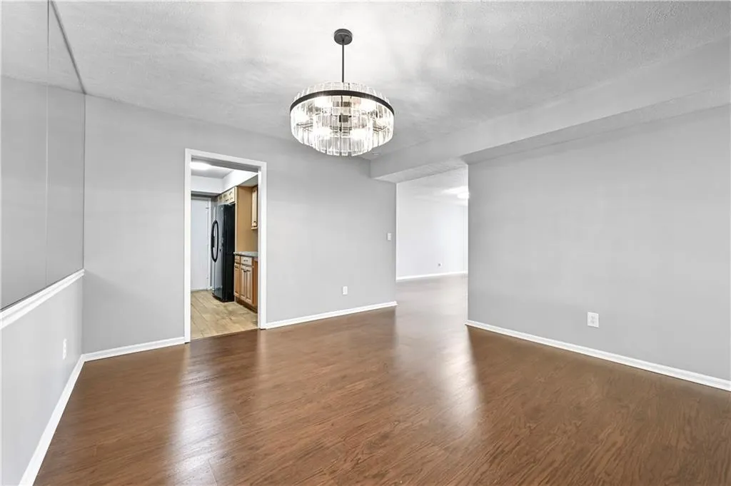 Empty room featuring an inviting chandelier, hardwood / wood-style floors, and a textured ceiling