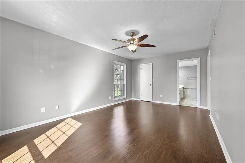 Empty room with ceiling fan, dark hardwood / wood-style floors, and a textured ceiling