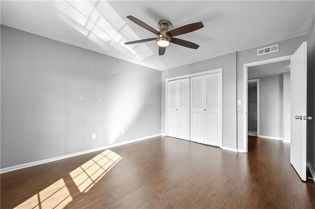 Unfurnished bedroom with ceiling fan, dark hardwood / wood-style flooring, and a closet