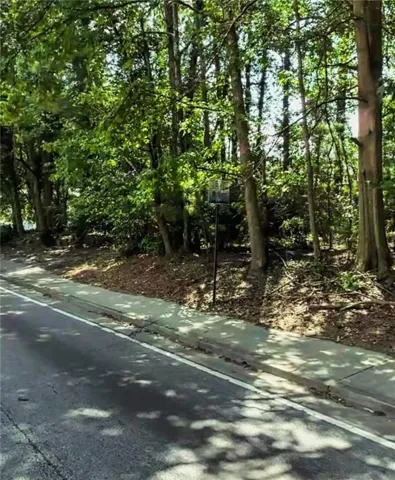 Roadside property with mature trees and a sidewalk