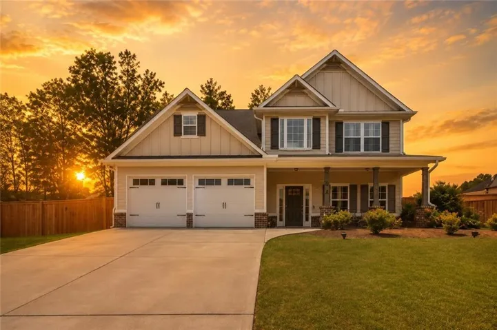 Two-story residence featuring a covered front porch with stone accents, a two-car garage, and a concrete driveway