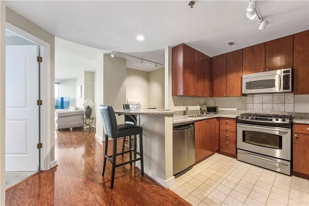 Kitchen featuring wood cabinetry, stainless steel appliances, granite countertops, and a tiled backsplash