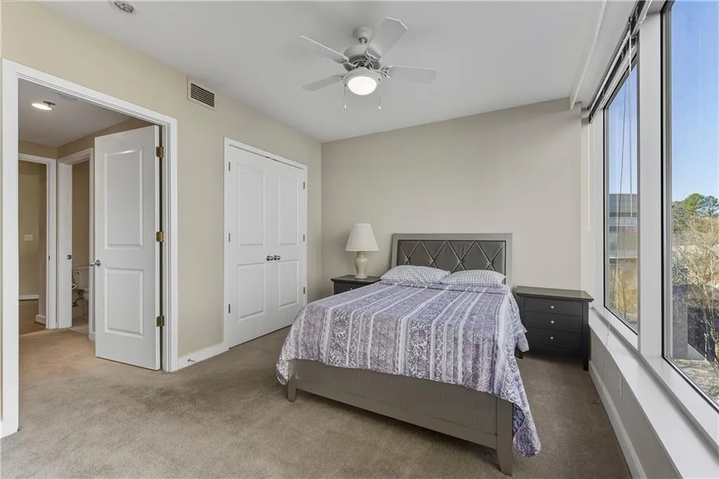 Wall-to-wall carpeting, full-height window, white ceiling fan with integrated lighting, solid core interior doors, and a built-in closet with double doors