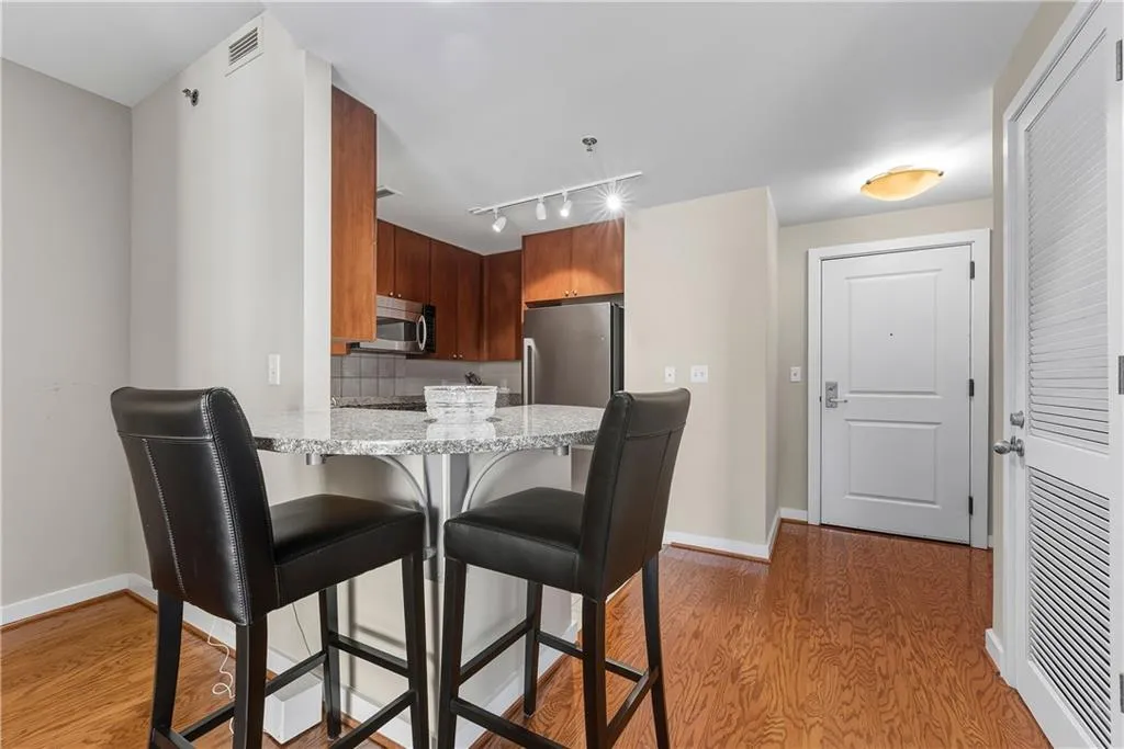 Wood-finish flooring, granite countertop, stainless steel appliances, wood cabinetry, and track lighting