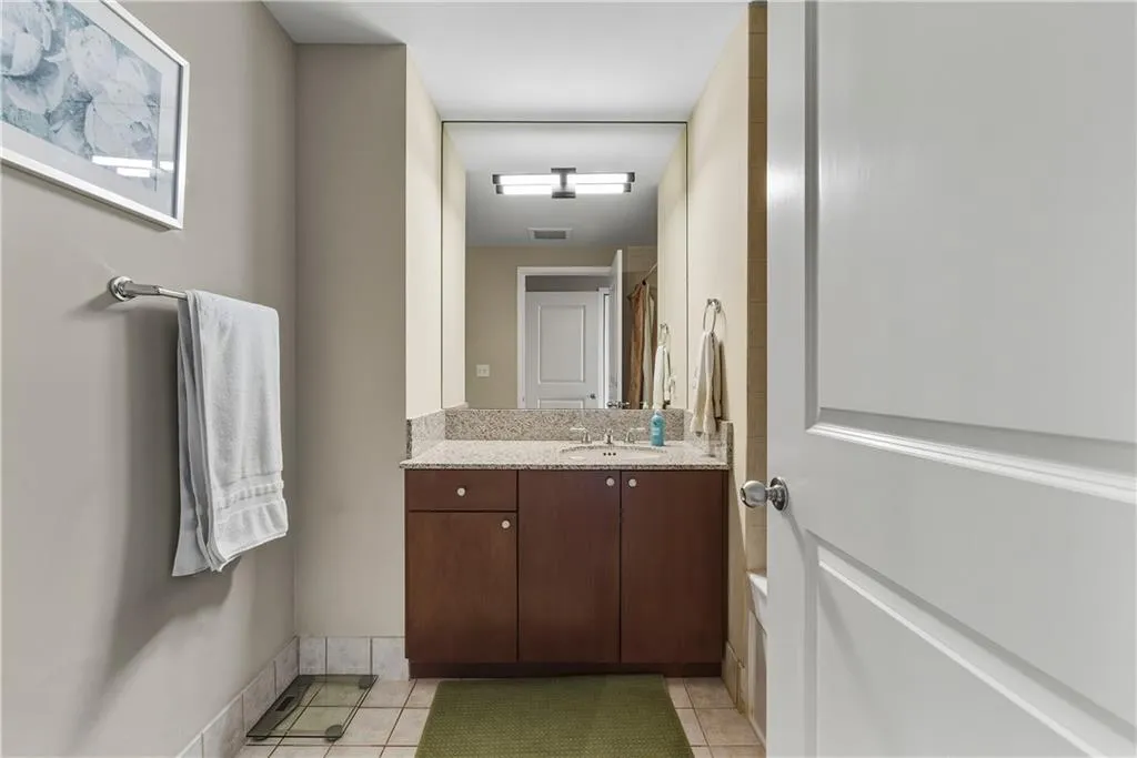 Vanity with integrated sink, stone countertop, wood-finish cabinetry, and tiled flooring