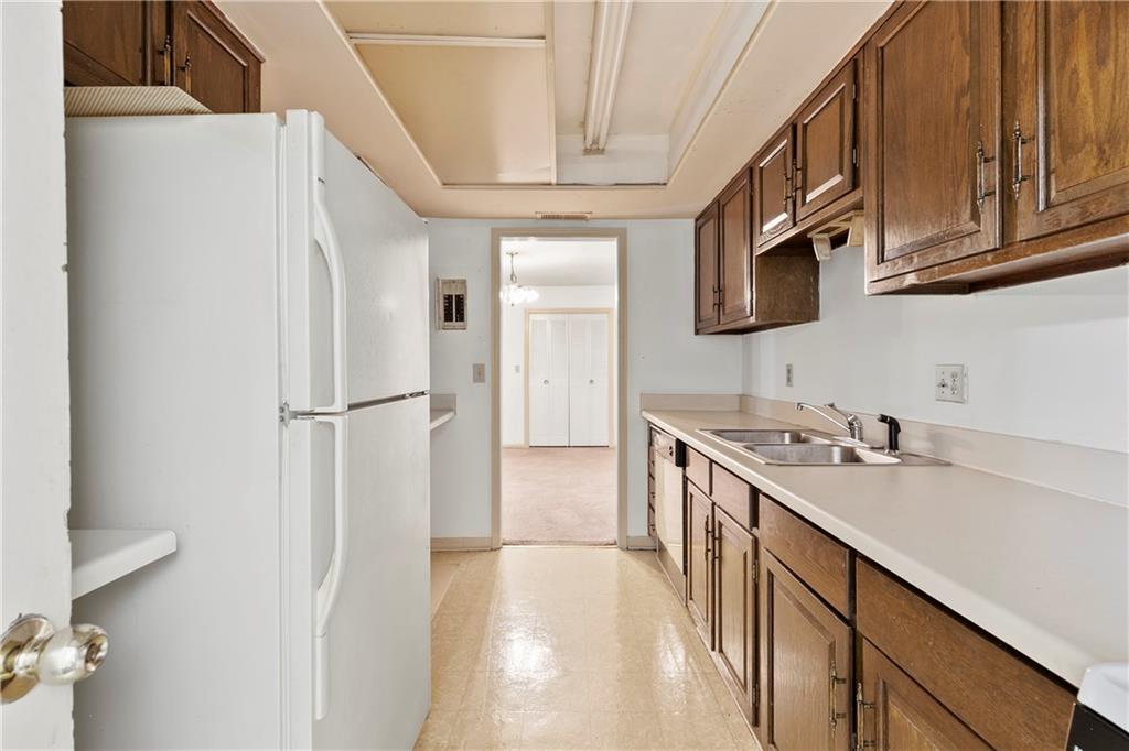 Kitchen with light tile flooring, sink, and white appliances