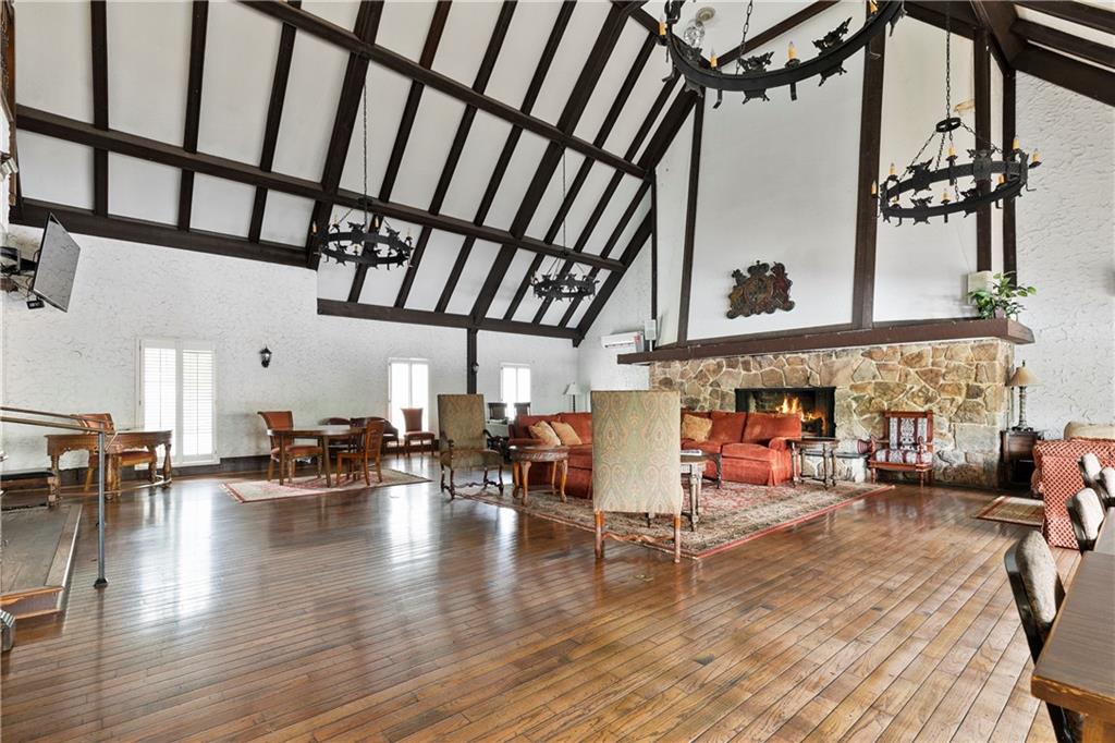 Living room with beam ceiling, high vaulted ceiling, an inviting chandelier, dark hardwood / wood-style floors, and a fireplace