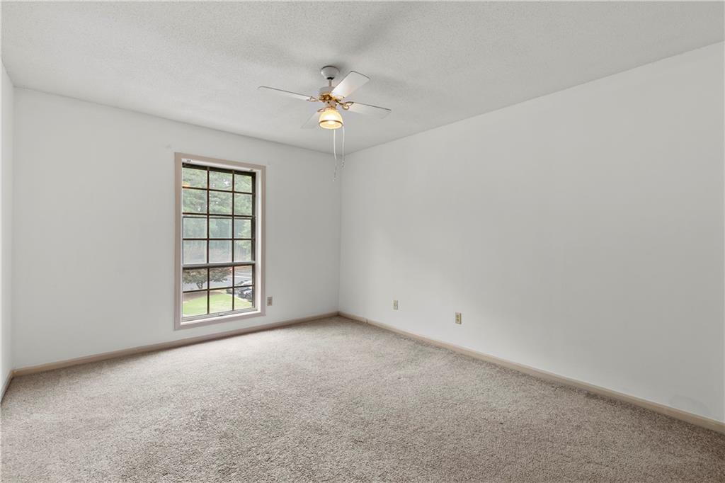 Unfurnished room featuring ceiling fan, a textured ceiling, and light carpet