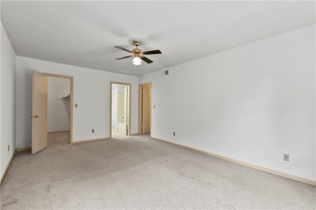 Unfurnished bedroom with a walk in closet, light carpet, a closet, and ceiling fan