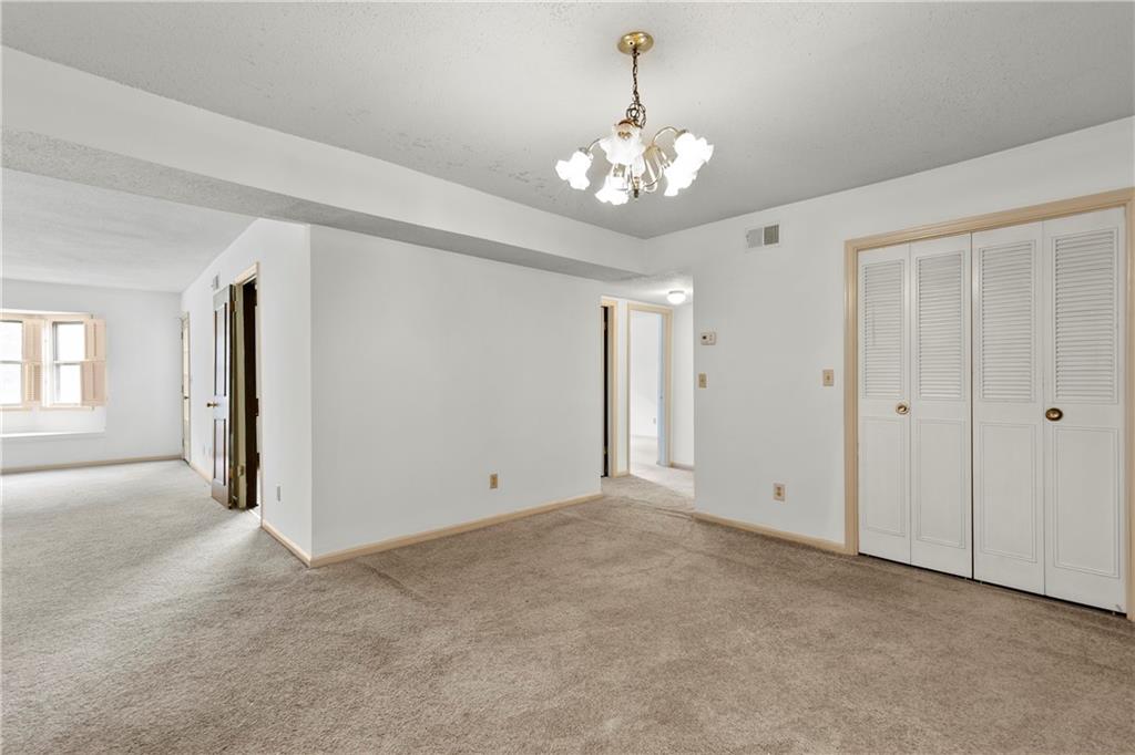 Unfurnished bedroom with a notable chandelier, a closet, and light colored carpet