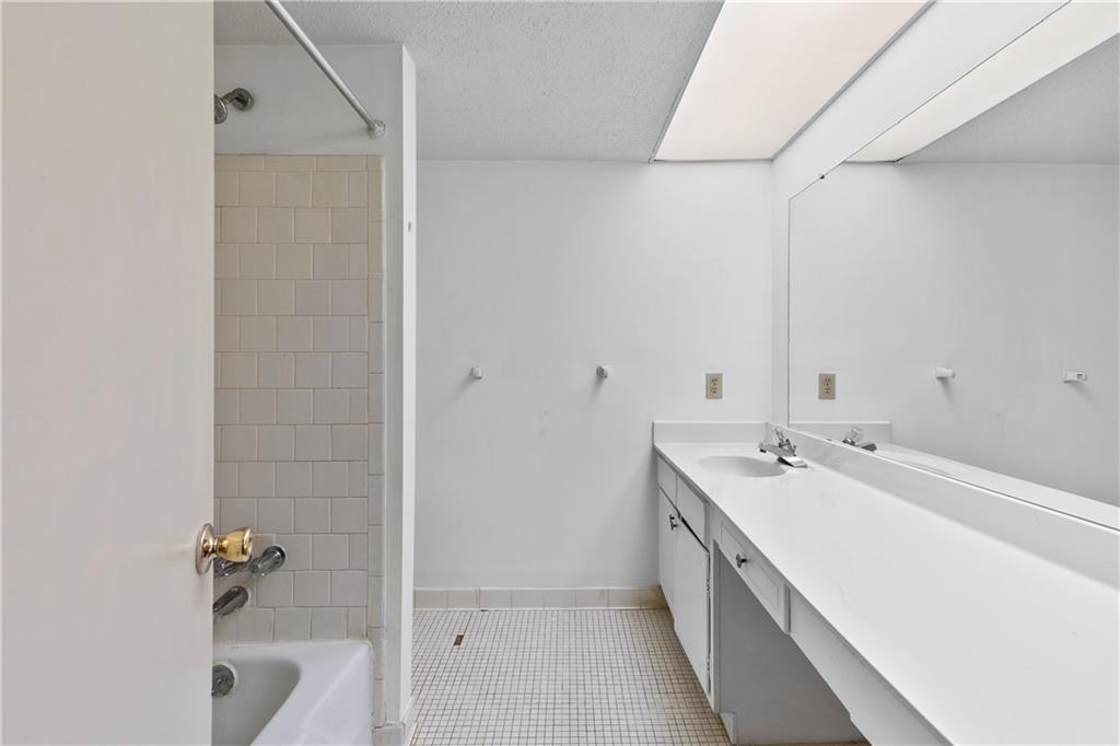 Bathroom with tiled shower / bath combo, vanity, a textured ceiling, and tile floors