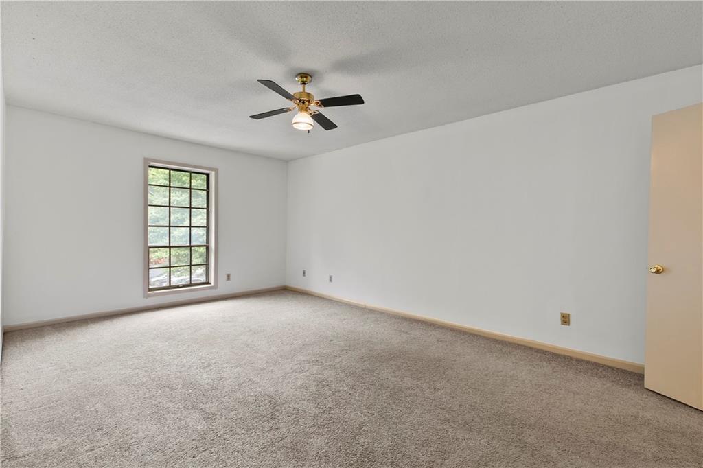 Unfurnished room with light colored carpet, ceiling fan, and a textured ceiling