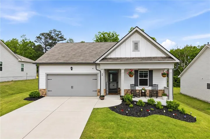 White siding exterior with a covered porch, stone accents, and a single-car garage