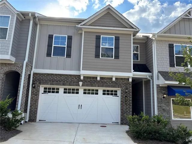 Exterior facade featuring brick accents, board and batten siding, and a white garage door with decorative hardware